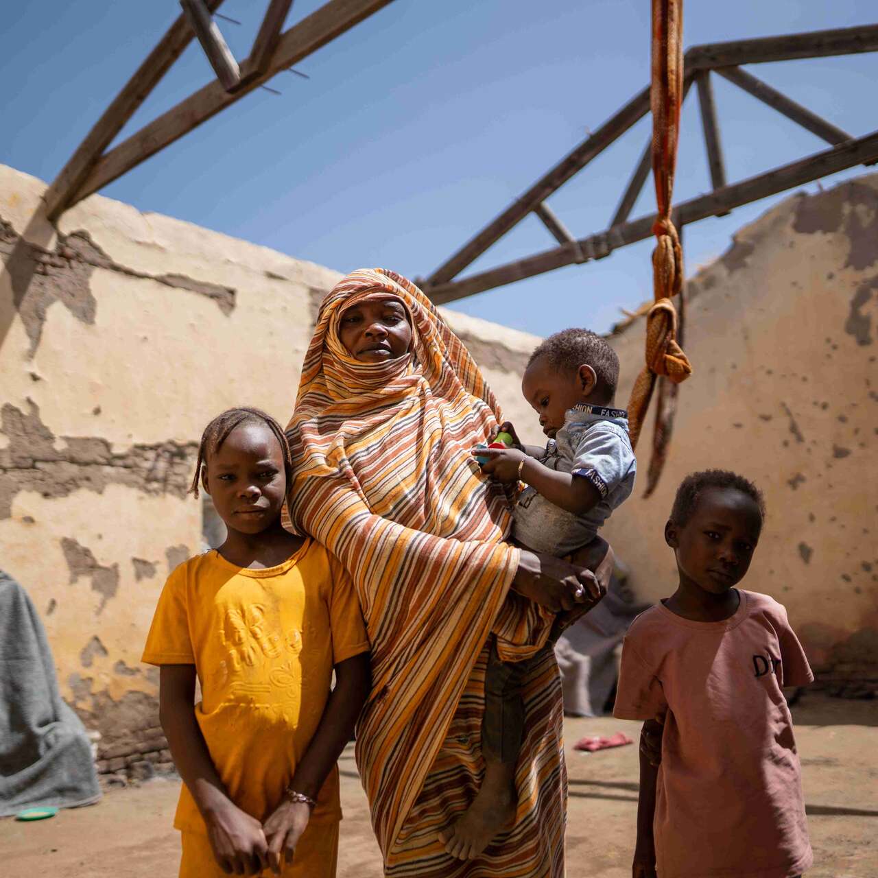 Altuma, 45, and her children stand inside their roofless shelter in Gedaref, Sudan.